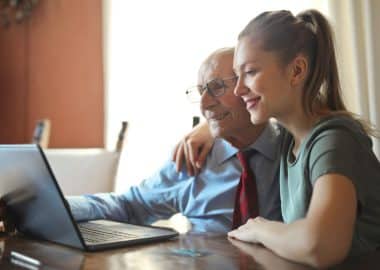 Grootvader en kleinkind kijken naar laptop - Laat mensen (patiënten) helpen!